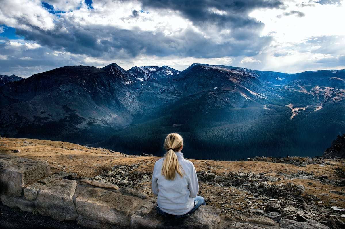 Woman sitting on a ledge facing mountains - taking some me time