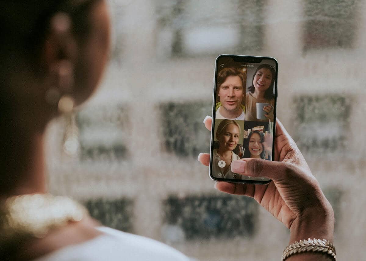 Overcome Your Job Search Blues - Woman holding a phone showing a video conference with 4 friends