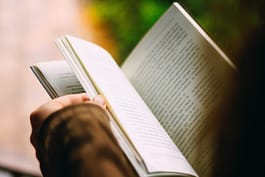 Person reading book - image shot from over person's head - Top 5 Reasons People Should Read Daily