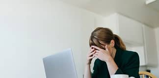 Woman sitting across from laptop with hands over her eyes - Actions to overcome job search blues