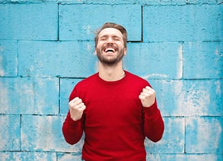Man in red sweater smiling with fists closed - Outstanding Ways To Seize The Day