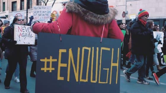 Protester carrying #ENOUGH sign - Making Money Online