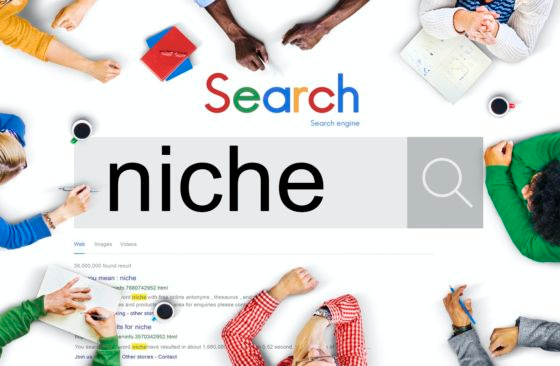 Work desk with many hands surrounding a Google search box with Niche on it - Choosing Your Blogging Niche