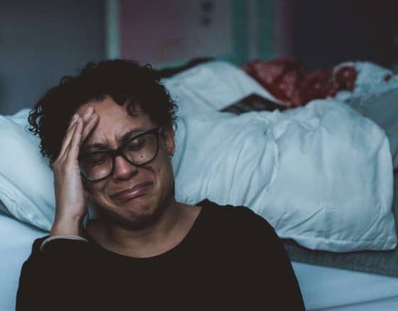 Woman sitting by bed crying, overwhelmed - Outstanding Ways To Seize The Day