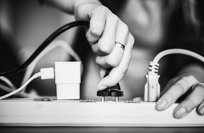 Person plugging in a device onto a surge protector