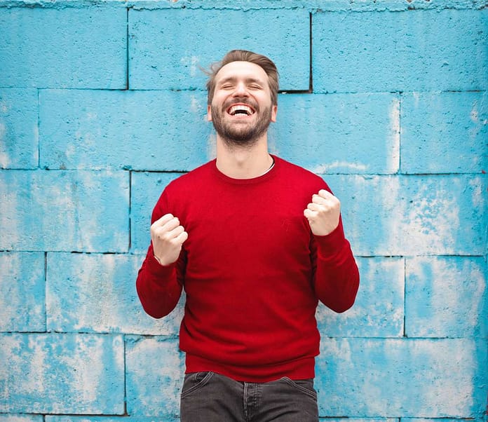 Man in red sweater smiling with fists closed - Outstanding Ways To Seize The Day