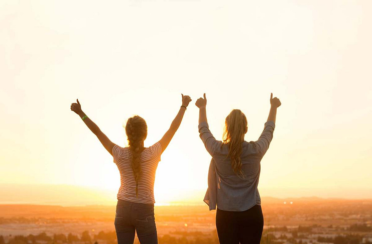 Two women with hands raised, happy with their achievement - 11 Simple Ways to Be Your Very Best