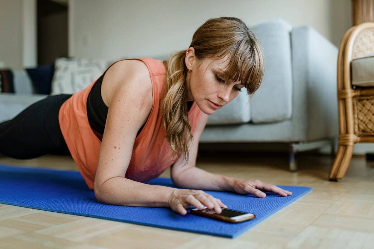 Overcome Your Job Search Blues - Woman on a mat following a training exercise app on her phone