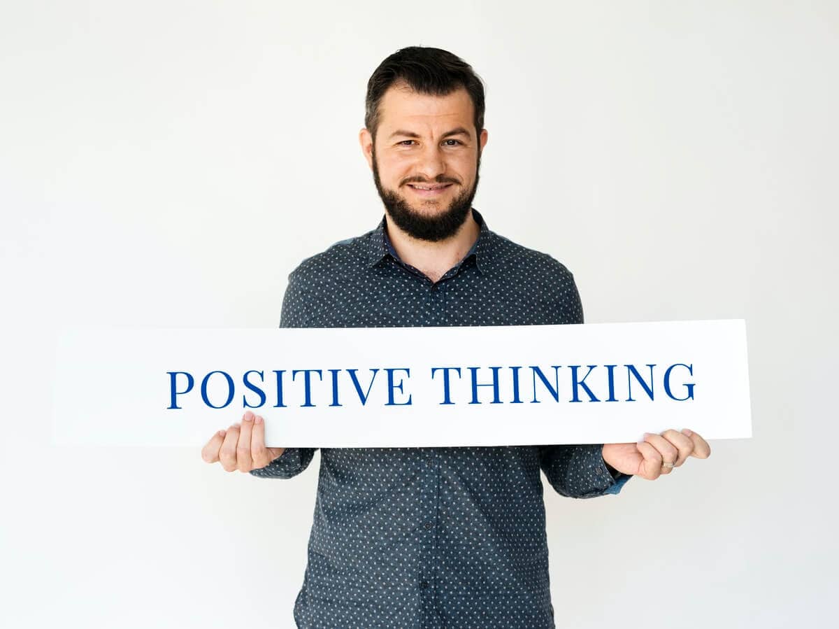 Overcome Your Job Search Blues - A man carrying a banner saying "Positive Thinking" - overcome your job hunting woes