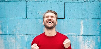 Man in red sweater smiling with fists closed - Outstanding Ways To Seize The Day