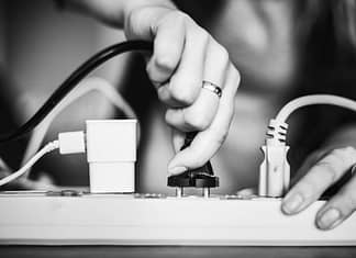 Person plugging in a device onto a surge protector